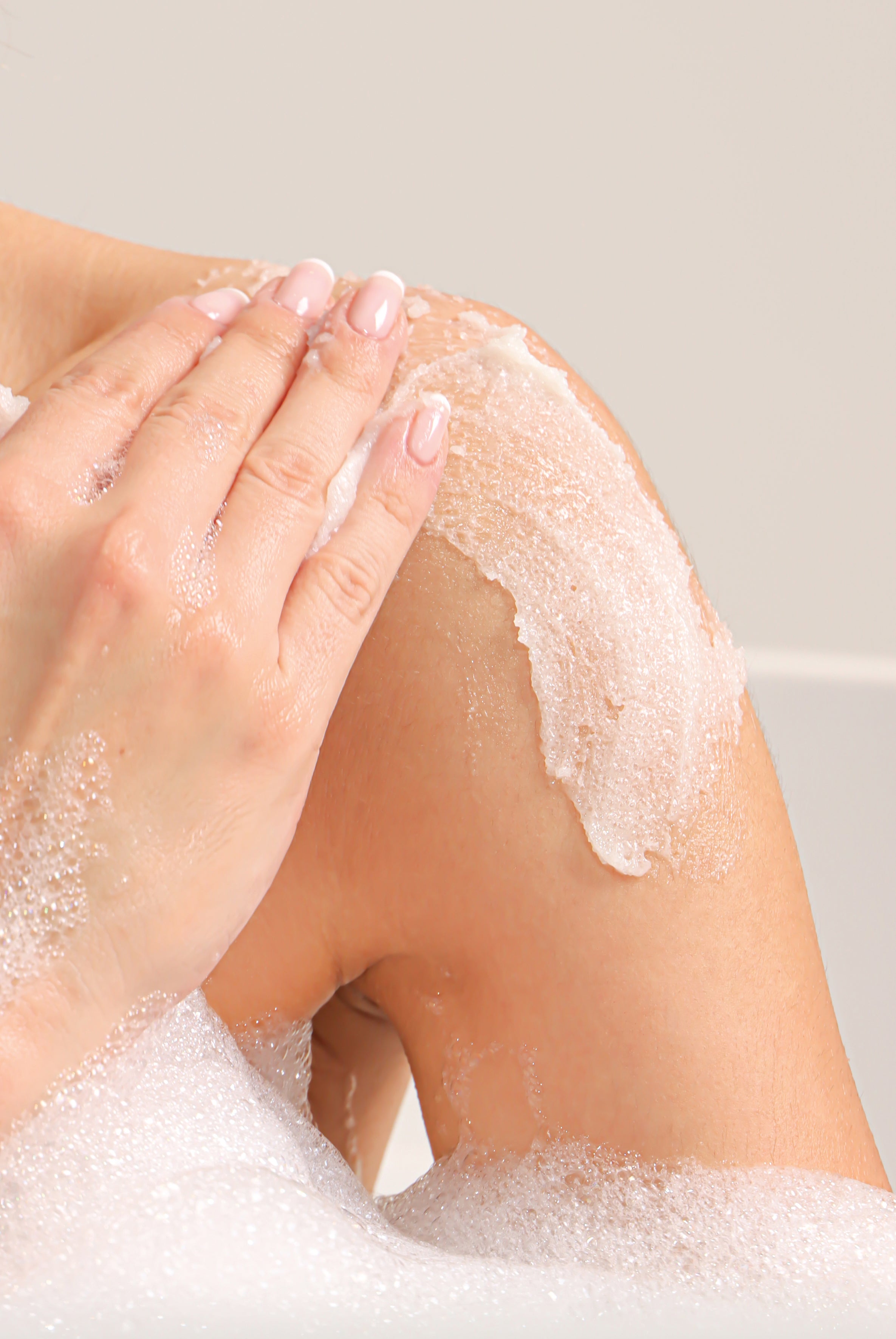 A woman applying the Fresh Coconut Pulp Body Scrub on her shoulders.