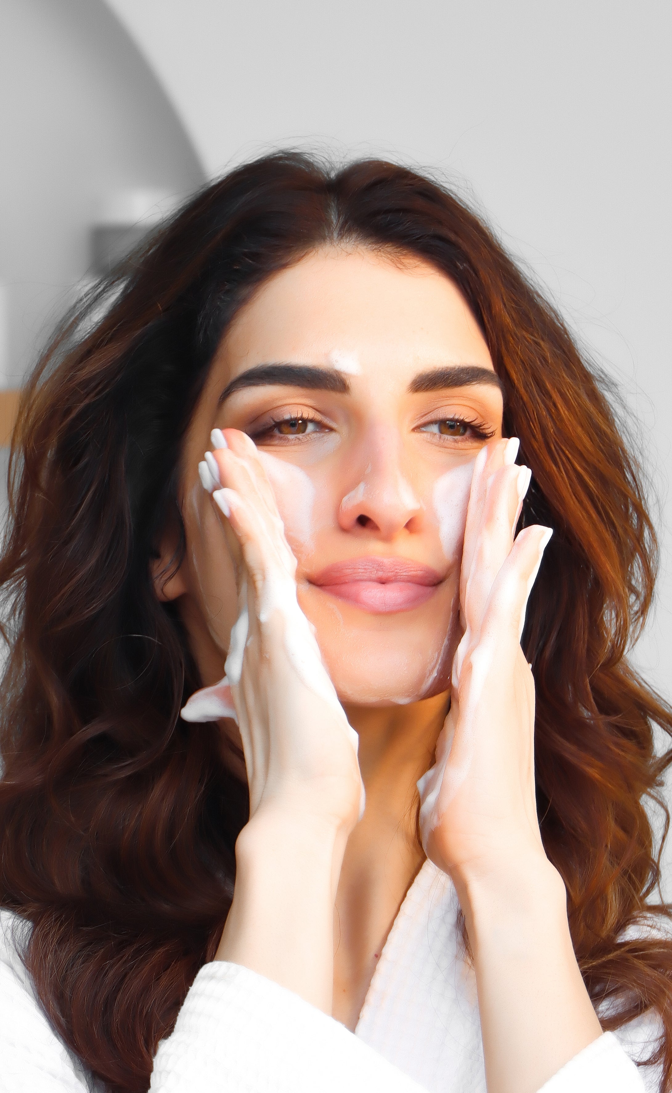 A woman cleans her face with the Foamjito Cleansing Foam.